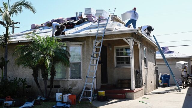 A roofing crew installs shingles on a small single-story home in Lakewood, CA.