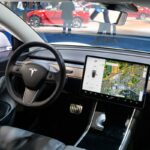 Tesla Model 3 compact full electric car interior with a large touch screen on the dashboard.