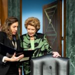 Senator Debbie Stabenow speaks with an aide before a committee meeting