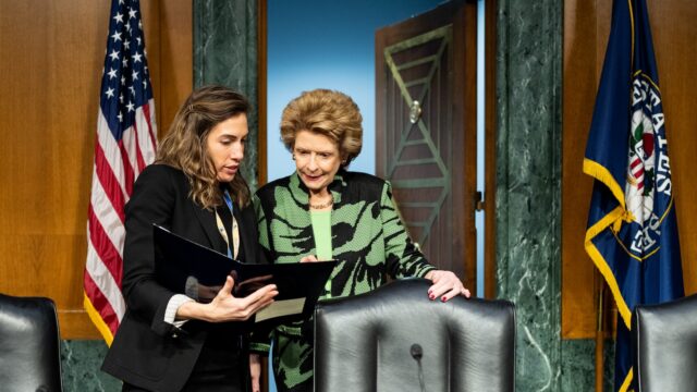 Senator Debbie Stabenow speaks with an aide before a committee meeting