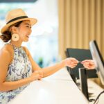 Side View of Young Asian women traveler, check in or paying at front desk. Her receiving a hotel room key from Customer service representative, used in post about utu