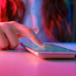 person touching a smartphone laying on a table.