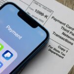 Payment apps like PayPal and Venmo are seen on an iPhone on top of Form 1099-k.