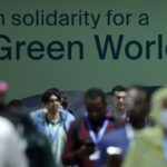 A group of people walk in front a banner that reads: