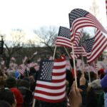 American flags waving in crowd of people.