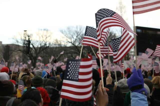 American flags waving in crowd of people.