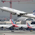 A United Airlines plane takes off above American Airlines planes on the tarmac at Los Angeles International Airport (LAX) on October 1, 2020