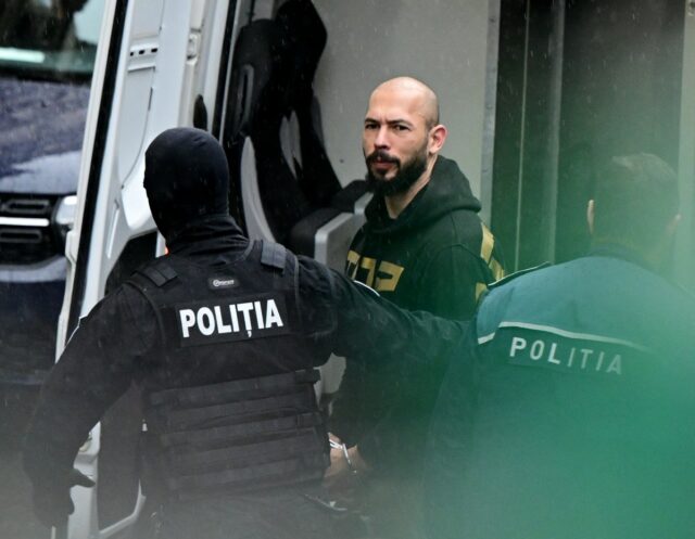 a photo of British-US former professional kickboxer and controversial influencer Andrew Tate (C) led by police officers to the Court of Appeal in Bucharest, Romania in early 2024.