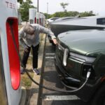 Rivian SUV charging at a Tesla Supercharger.