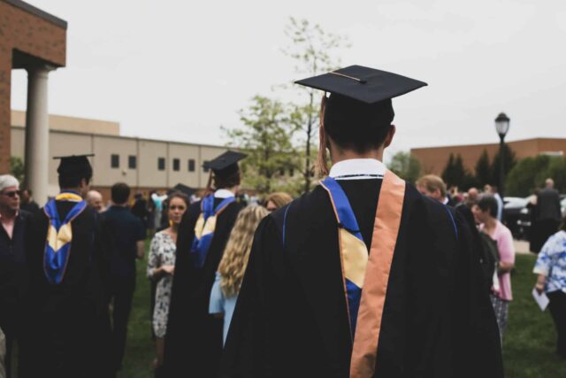 Student wearing graduation gown from behind.