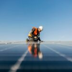 A handyman on the rooftop installing solar panels.