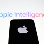 In this photo illustration, the 'Apple' logo is displayed on a mobile phone screen in front of a computer screen displaying Apple Intelligence logo.