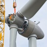 A crane positions the rotor of a wind turbine during construction.