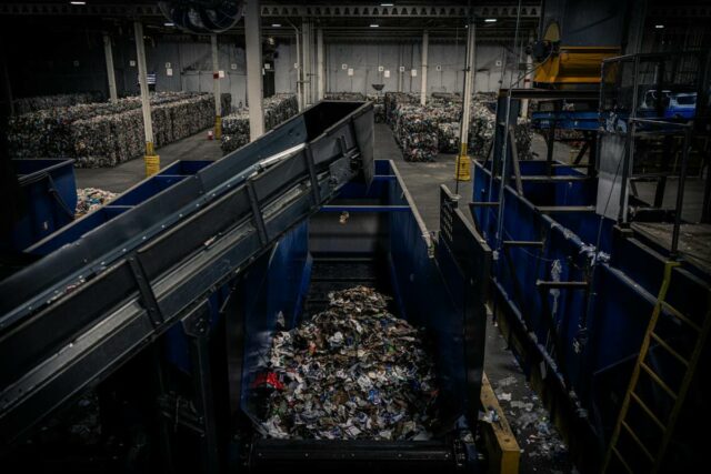 A conveyor belt moves trash inside a recycling facility.