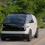 Two Canoo EVs drive on a road in Bentonville, Arkansas.