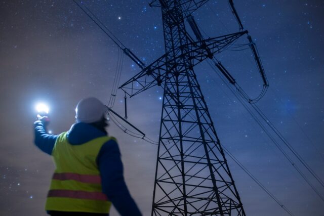 High voltage engineer working on power lines at night.