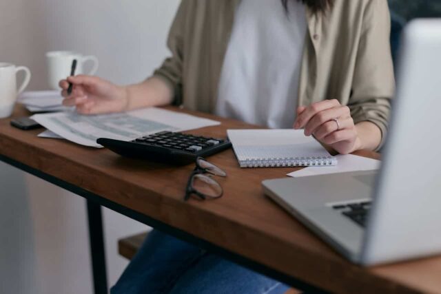 Woman sitting at desk with calculator making payment.