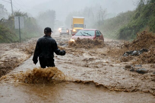 a local resident walks out into fast flowing waters to assist a stranded driver in a stretch of flooded road as tropical storm helene strikes on the outskirts of boone north carolina september 27 photo reuters