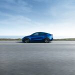 Blue tesla model y driving on a highway, view from the side