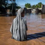 A woman wades through flood waters that inundated a residential area in Garissa, Kenya, following torrential rains in May, 2024.