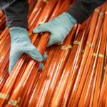 A worker lifts a bundle of copper windings.