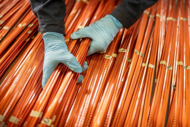 A worker lifts a bundle of copper windings.