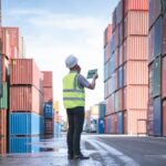 Engineer and tablet at Containers yard from Cargo freight ship for import export, used in a post about Freightify