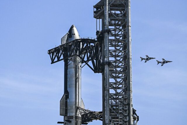 TOPSHOT - US billionaire businessman and pilot Jared Isaacman flies in formation aboard a fighter jet over the SpaceX Starship spacecraft, before his third test flight from Starbase in Boca Chica, Texas, on March 13, 2024. Elon Musk's SpaceX announced it was eyeing March 14 as the earliest date for the next test launch of its giant Starship rocket, with which it hopes to one day colonize Mars. Two previous attempts have ended in spectacular explosions, though the company has adopted a rapid trial-and-error approach in order to accelerate development. (Photo by CHANDAN KHANNA/AFP via Getty Images)