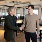 French CEO of AFP (Agence France Presse) Fabrice Fries (L) shakes hands with French founder of artificial intelligence start-up Mistral AI, Arthur Mensch at the Mistral headquarters in Paris, on January 15, 2025. AFP (Agence France-Presse) and Mistral have signed an agreement that allows the conversational robot of the French start-up that aims to become Europe's leading AI player to use the agency's news dispatches to answer its users' queries, they announced on January 16, 2025.