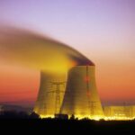 Nuclear power plant cooling towers emit steam at dusk.