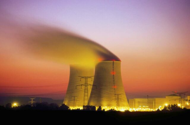 Nuclear power plant cooling towers emit steam at dusk.