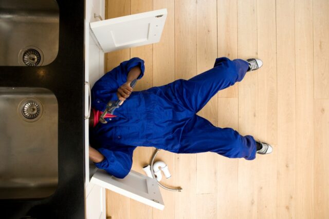 Plumber working under kitchen sink, overhead view