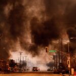 Black smoke fills the sky over a neighborhood burning in Los Angeles.