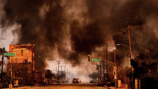 Black smoke fills the sky over a neighborhood burning in Los Angeles.