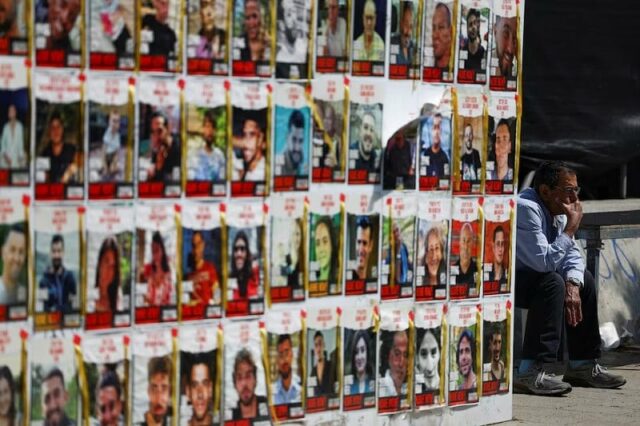 a man sits next to posters with images of hostages kidnapped in the deadly october 7 attack in tel aviv israel file photo reuters