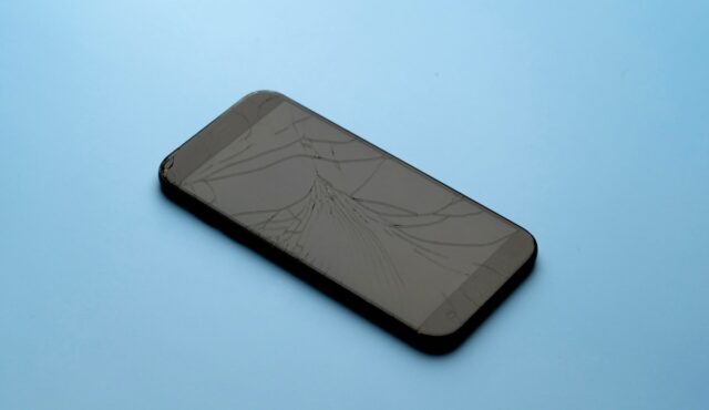 A broken phone on a blue table background.