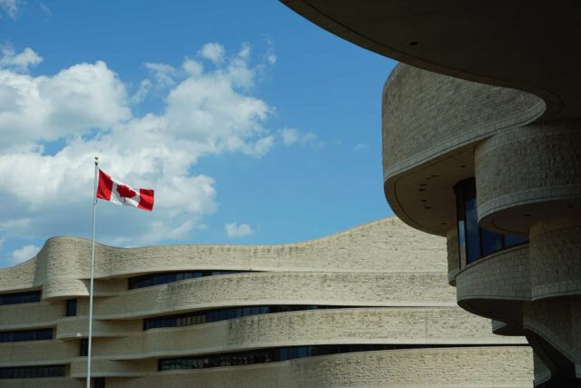 Canadian flag flying above buildings.