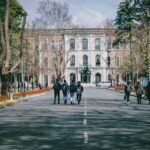 Students walking down road on university campus, facing away.