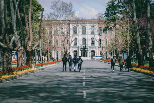 Students walking down road on university campus, facing away.