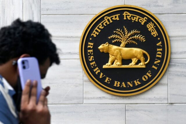 man on mobile phone walking past Reserve Bank of India sign