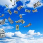 U.S. Money falling from a partly cloud sky.