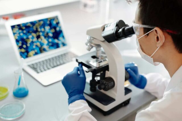 Female scientist looking into a microscope.